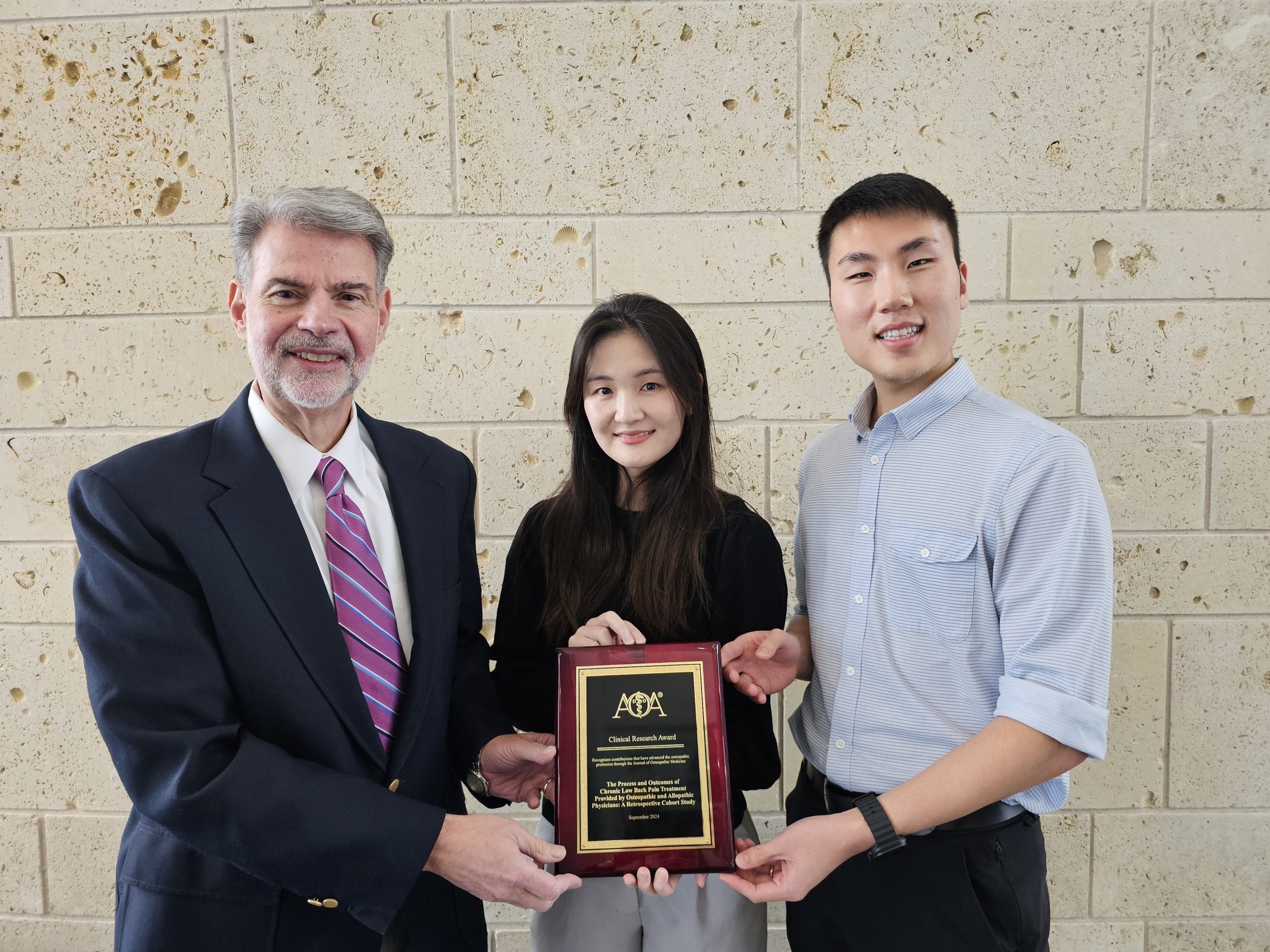 Photo of UNT Health TCOM's Dr. John licciardone holding a 2024 Clinical Research Award for the Process and Outcome of Chronic Low Back Pain Treatment along with two other students.