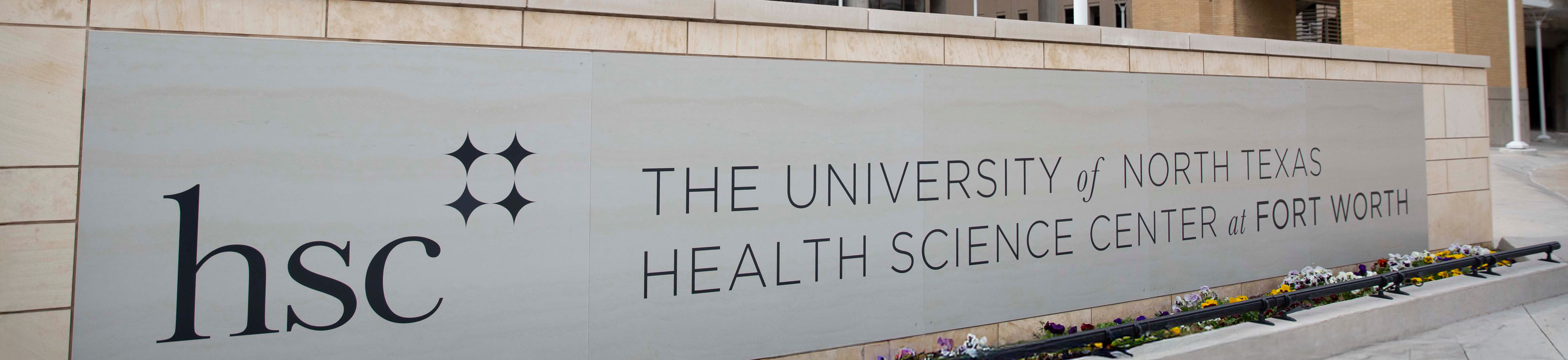 Photo of UNTHSC campus HSC logo signage marque on ground infront of building