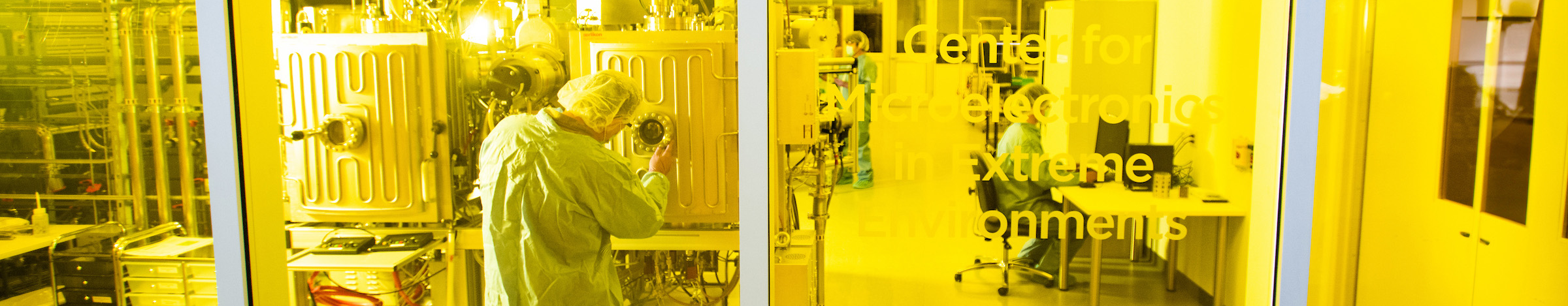 Top wide-narrow banner photo of a researcher in cleanroom attire works inside the UNT Center for Microelectronics in Extreme Environments semiconductor laboratory at Discovery Park.
