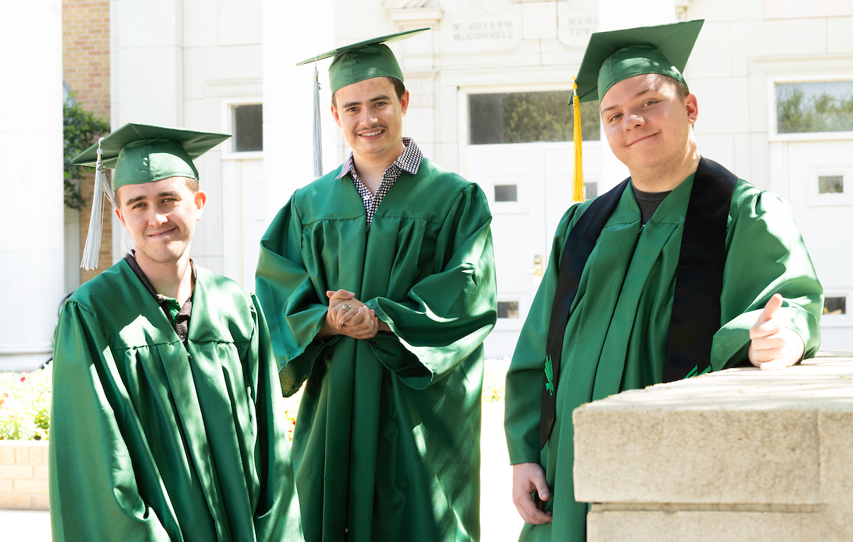 Photo (left to right): UNT's John Martin, Noah Rahn, and Alex Bartolo standing dressed in their green graduation cap and gown