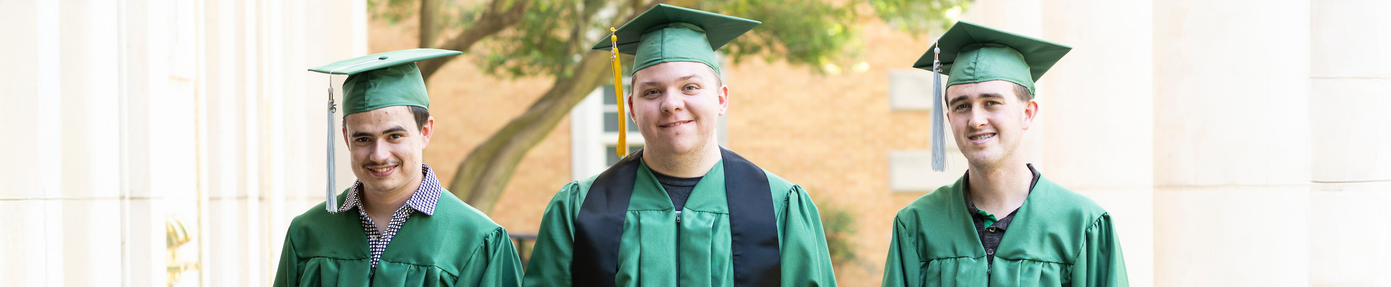 Top cropped horizontal banner photo (left to right): UNT's ELEVAR students Noah Rahn, Alex Bartolo, and John Martin each wearing their green graduation cap and gown standing outside