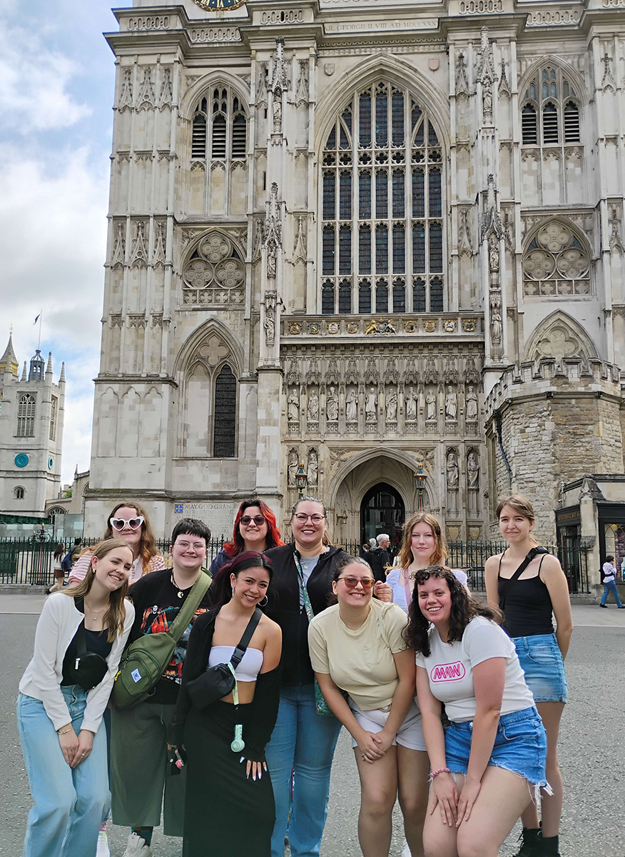 Photo of 10 UNT students facing the camera in two rows posing as they visit Westminster Abbey, London, England