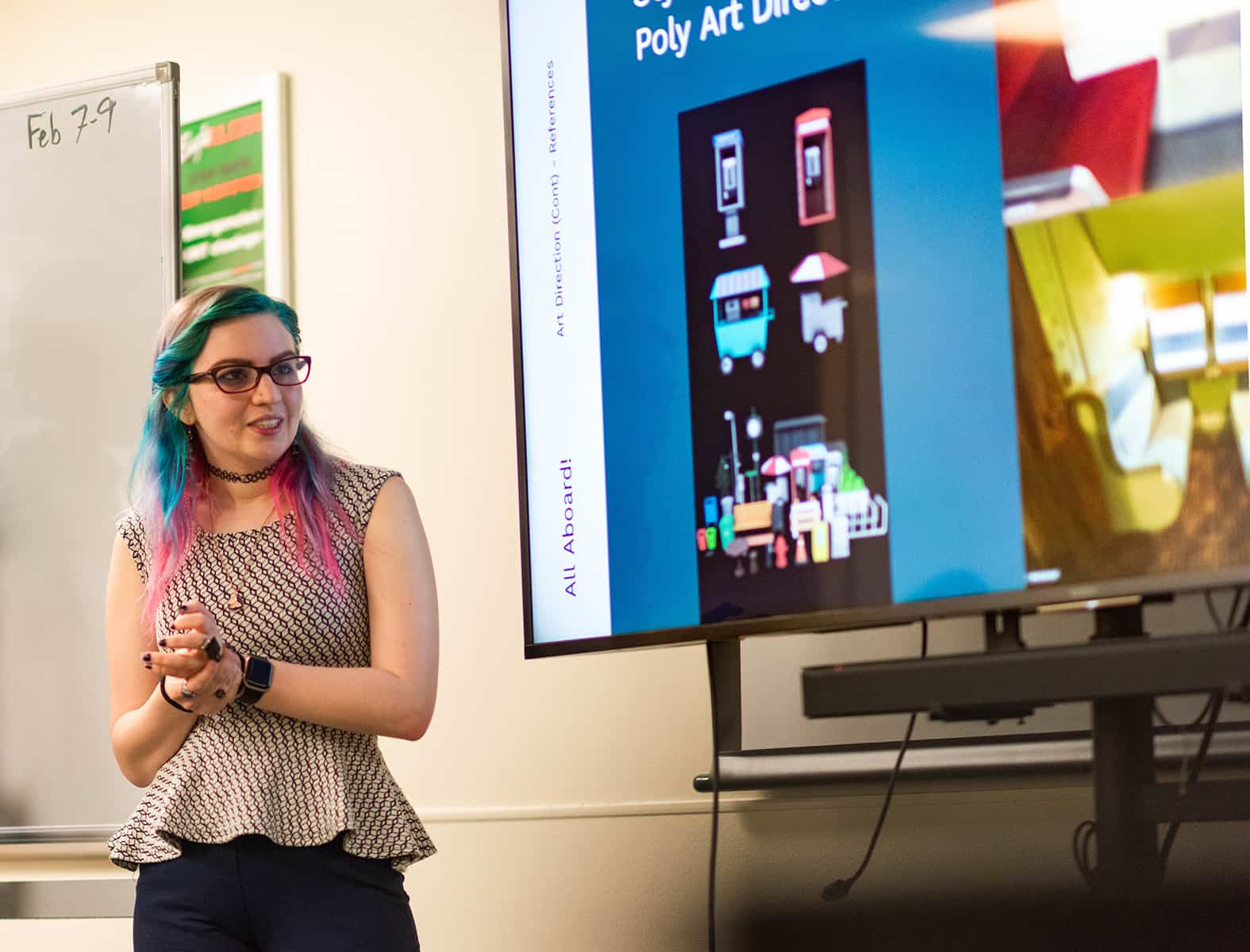 A Photo of UNT's Lillian Merrell discusses a game's preliminary art and narrative design on a large digital screen during a sprint review in the games pipeline capstone course