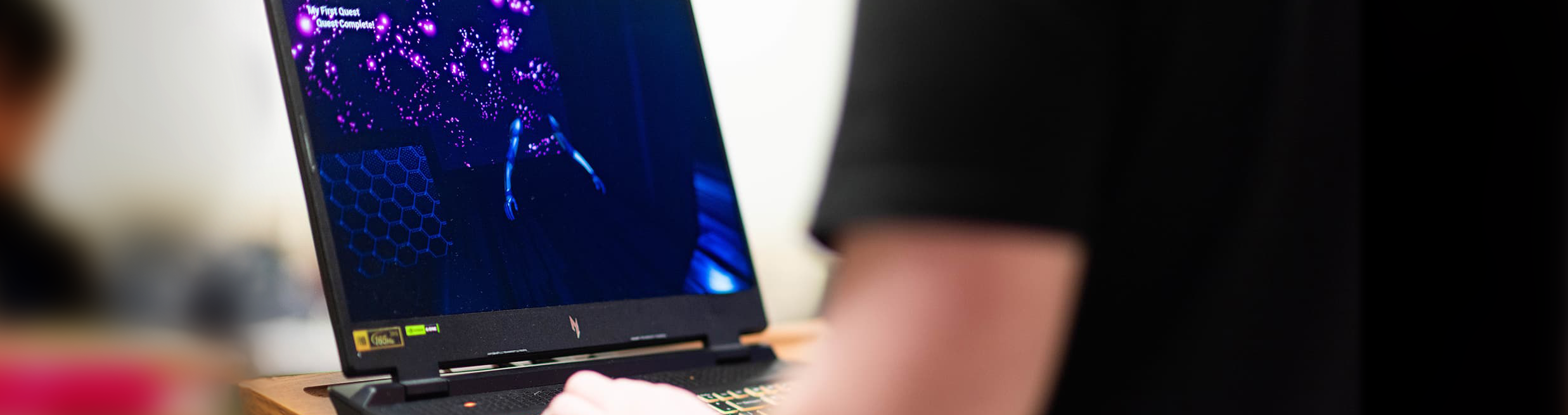 Top horizontal photo banner of UNT student working on their game design on a laptop computer 