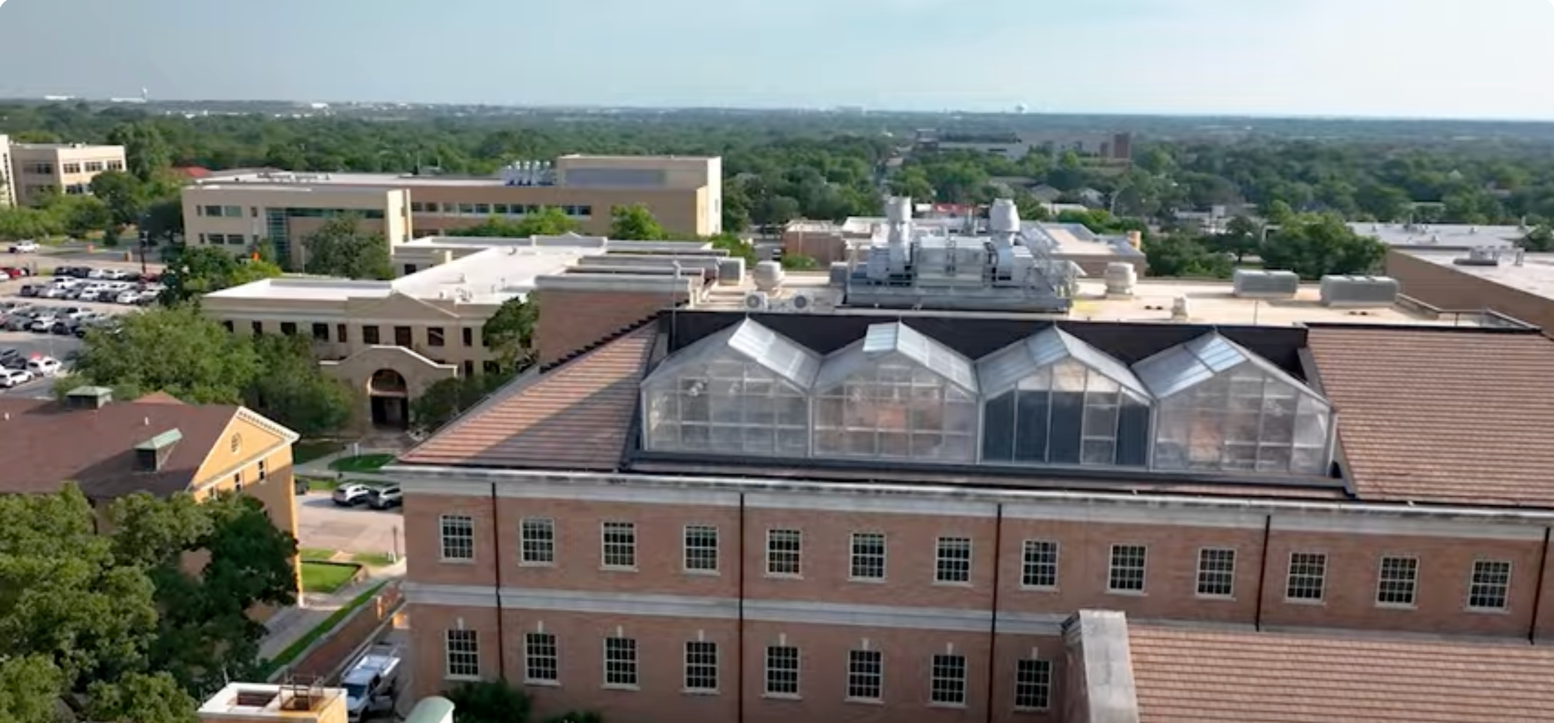 A view of the UNT campus with a rooftop greenhouse in the foreground with other multiple academic buildings in the background. 