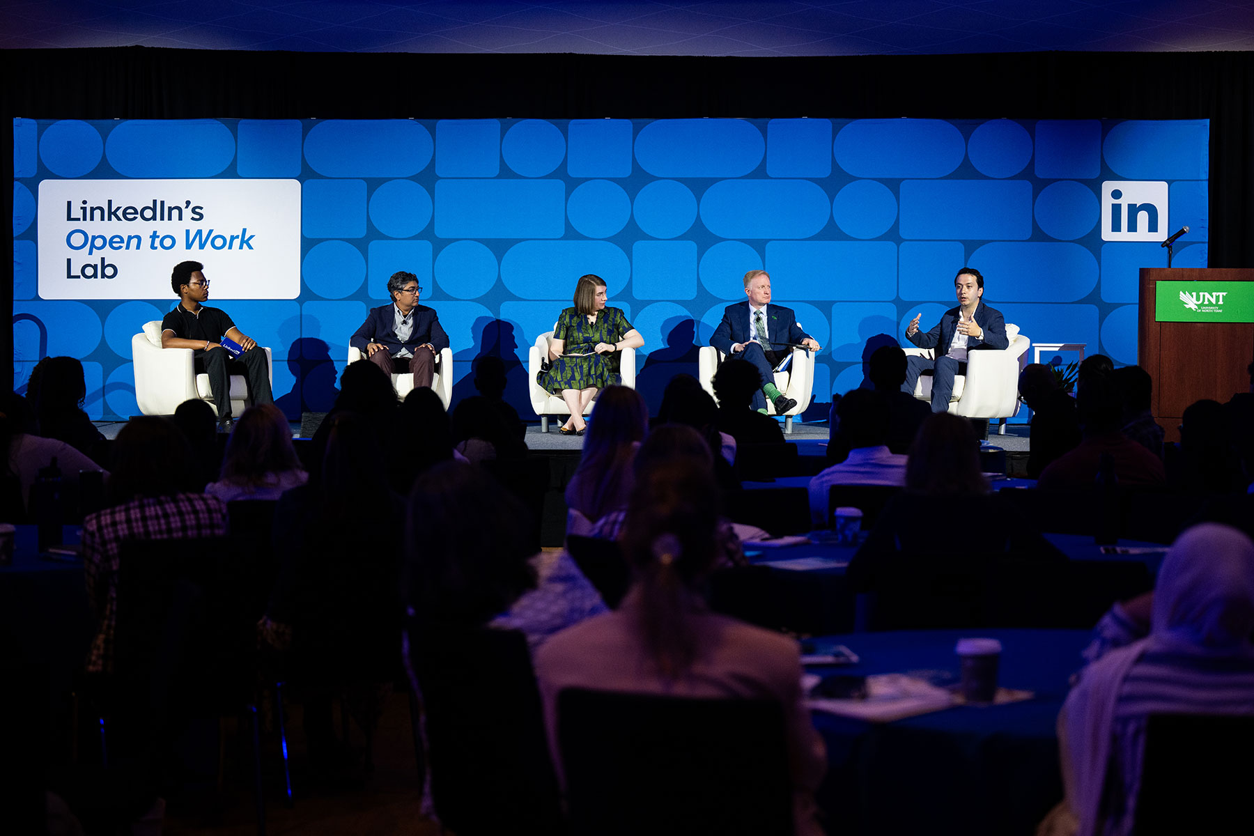 Full photo of five panelists seated on stage at LinkedIn's Open to Work Lab event at the University of North Texas event with a full audience.