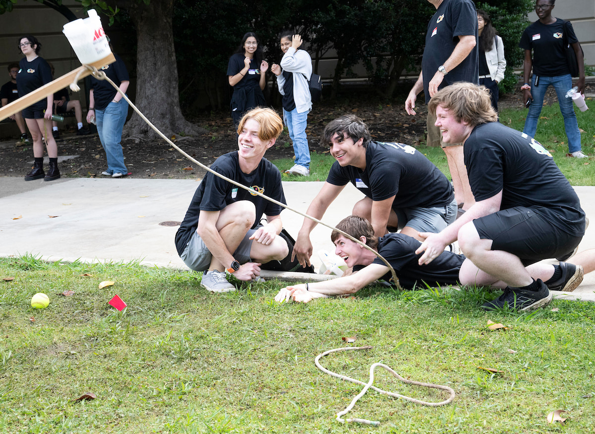 Photo of four students sitting and laying on the grass enjoying themselves after a catapult launch at UNT