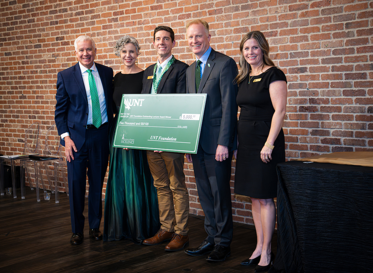 Photo of a  group of five people with UNT's Benjamin Graf in the middle holding a large check