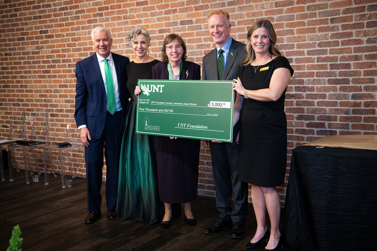 Photo of a group of five people with UNT's M. Jean Keller in the middle holding a large check