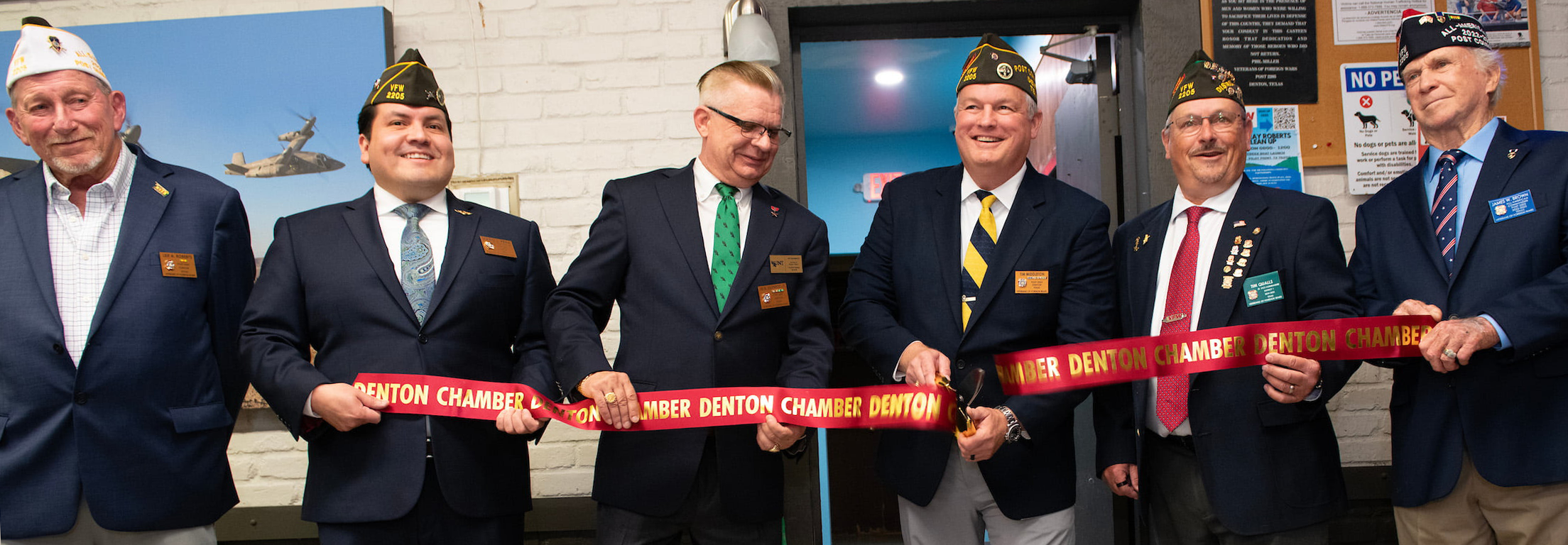 Top horizontal photo banner of six men holding a long ribbon with the middle man cutting it.