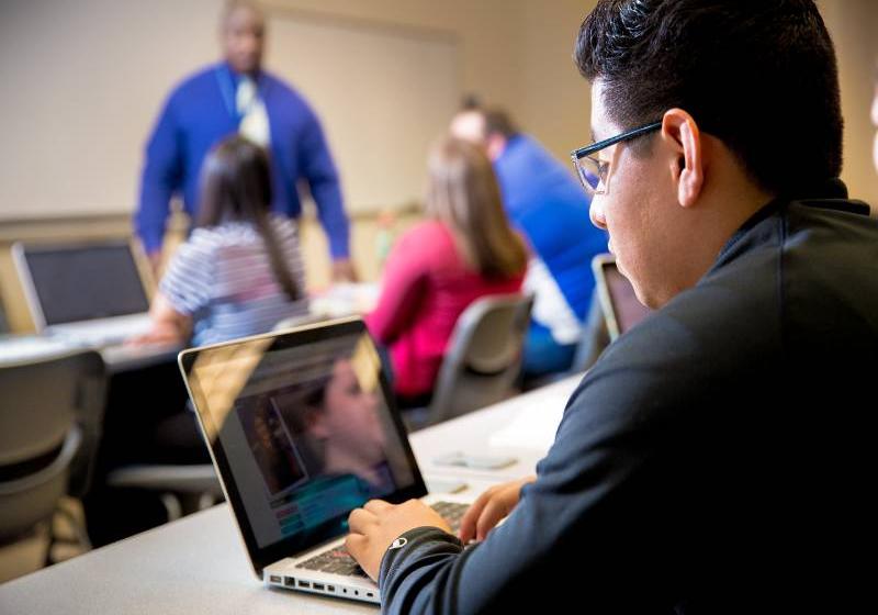 A photo of young man using a laptop to virtually communicate with his UNT Dallas professor.