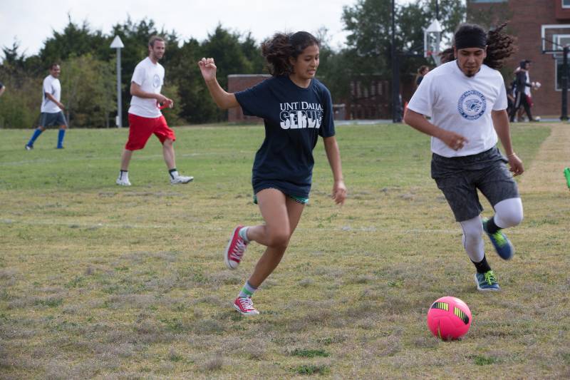 Photo of students and faculty battle on the soccer field in a friendly competition that forms bonds outside the classroom