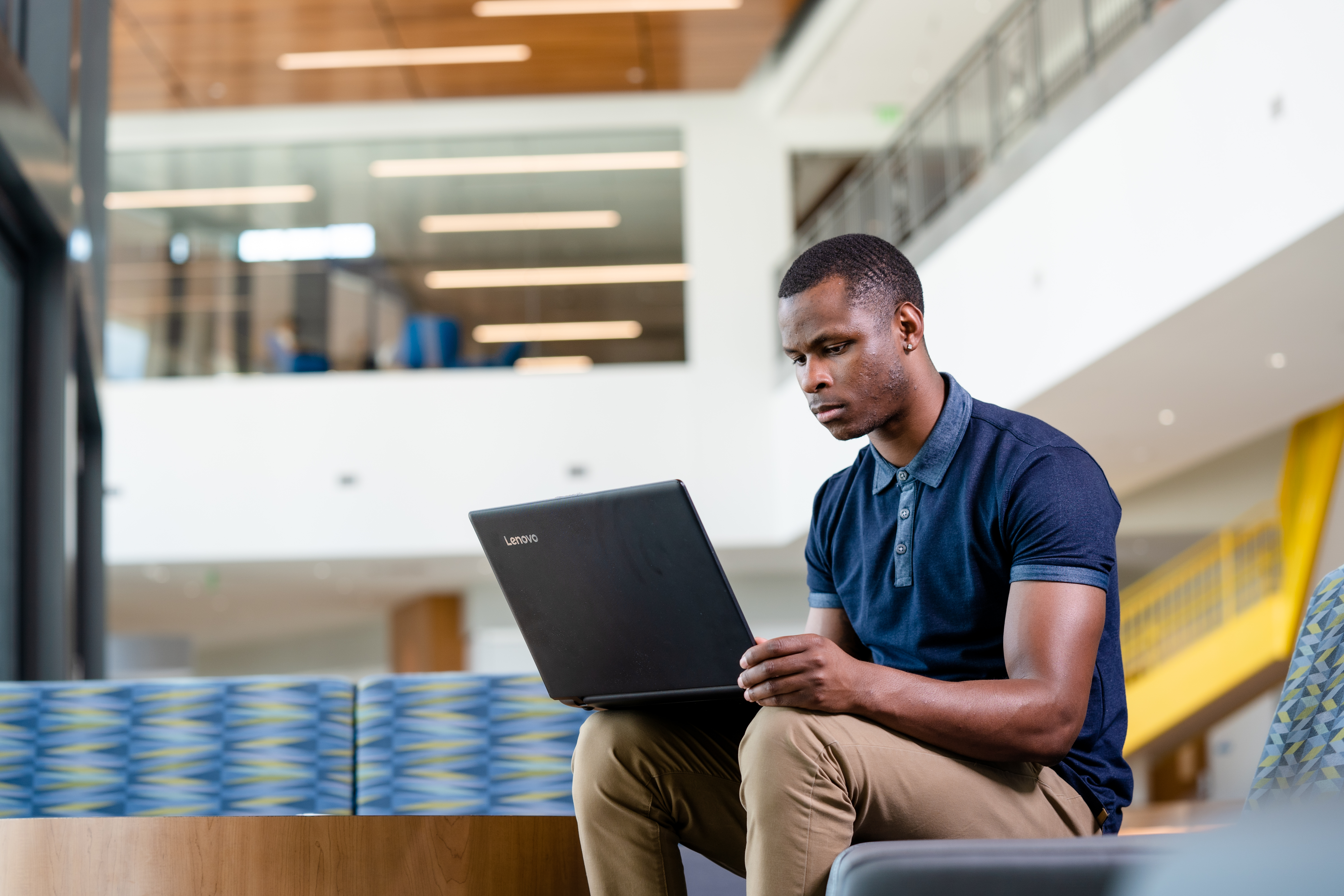 Photo of a UNT Dallas student working on a laptop in one of the campus building's atriums.