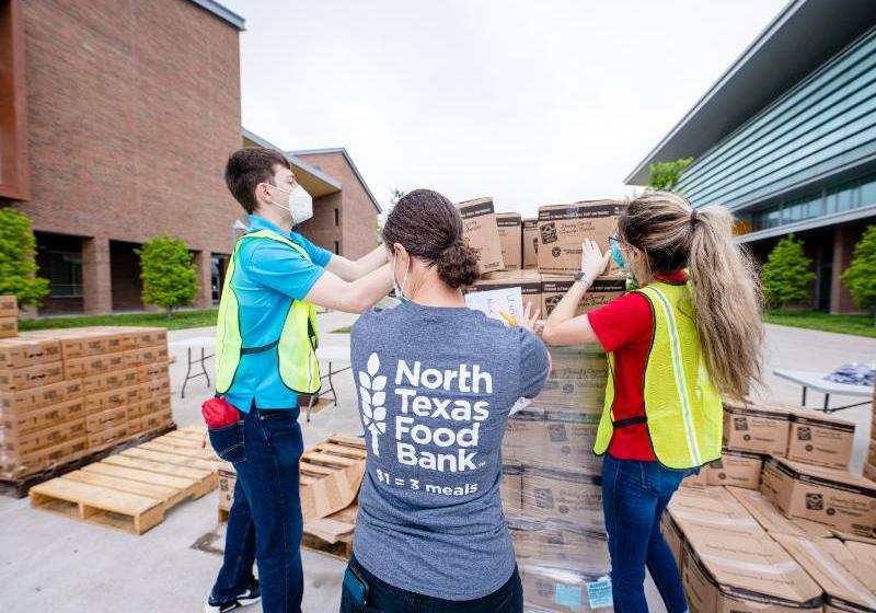 Photo of volunteers from North Texas Food Bank unload pallets of products at a mobile food pantry distribution on the UNT Dallas Campus 
