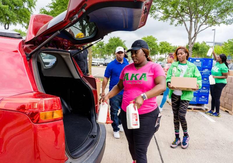 Photo of AKA Sorority Members from UNT Dallas load products into an SUV at mobile food pantry distribution 