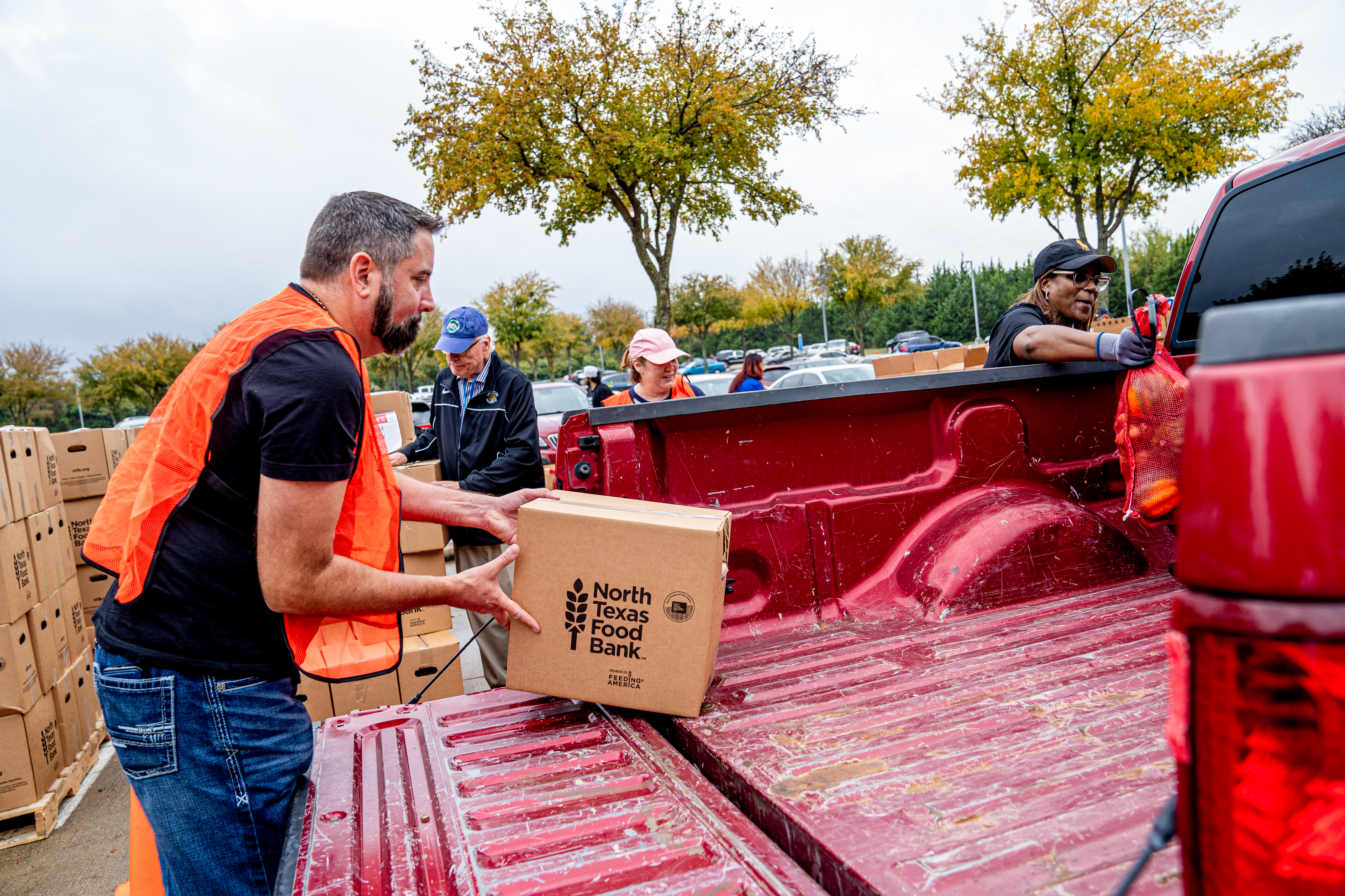 Photo of a UNT Dallas volunteer loading a "North Texas Food Bank" box of food into the back of a pickup