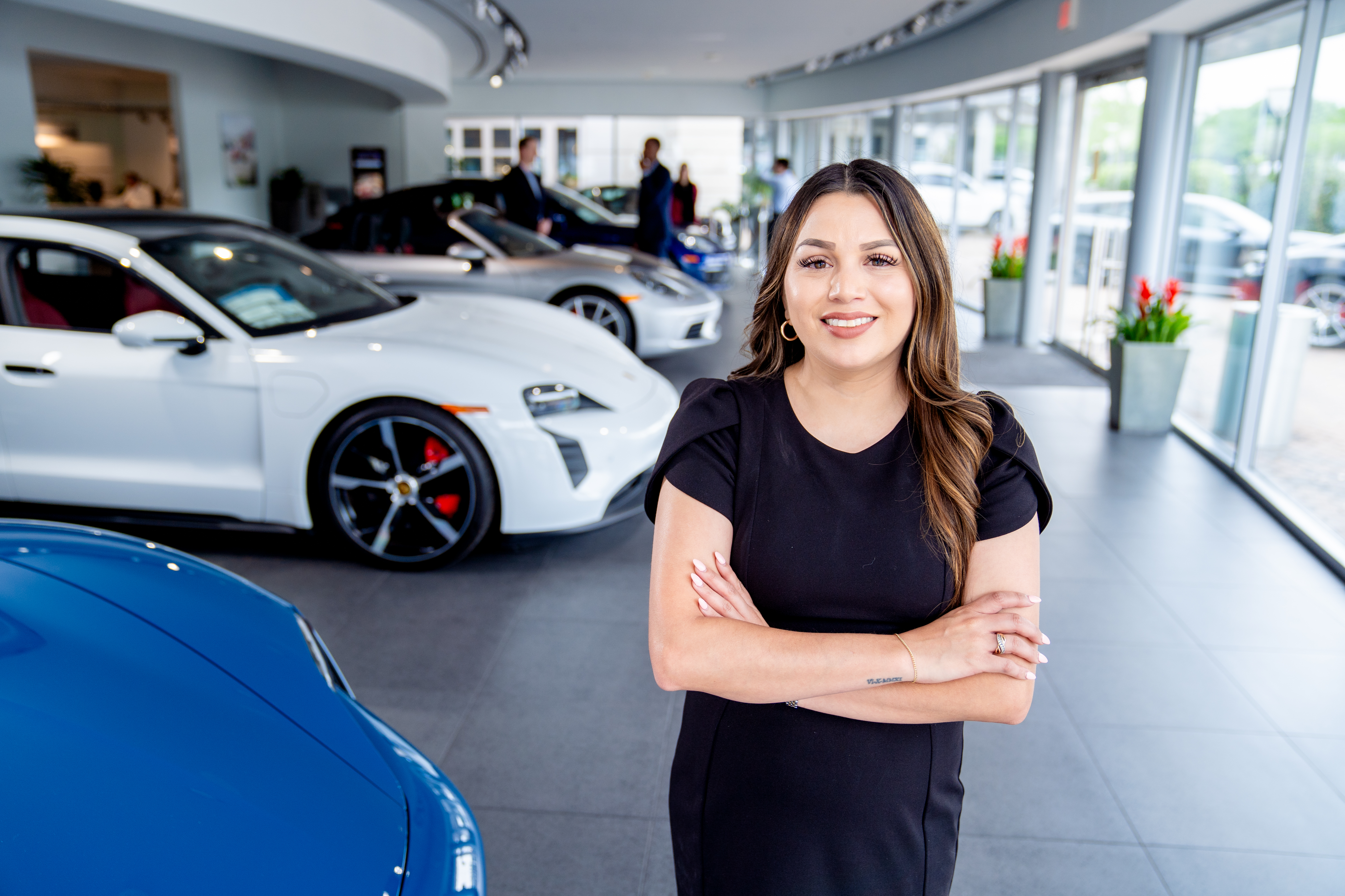 Photo of  UNT Dallas School of Business alumna Melissa Fogerson standing confidently inside a luxury car dealership showroom smiling.