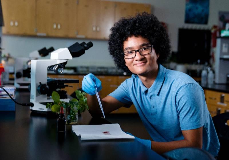 Photo of UNT Dallas's Myles Chung in a biology lab conducting an experiment 