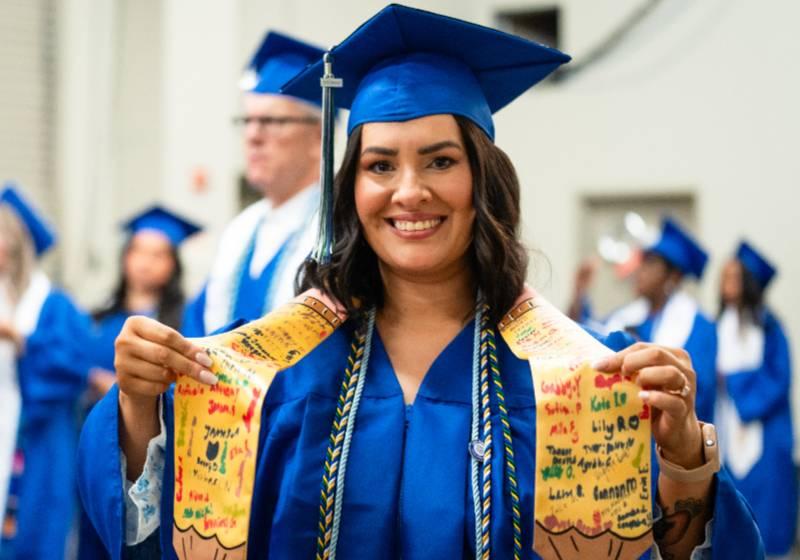 Photo of a 2025 UNT Dallas graduate proudly shows her special honors stole and cords 