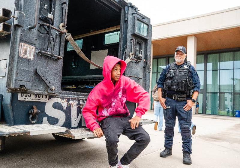 A student sits on the bumper of a SWAT truck Photo of a student sits on the bumper of a SWAT truck