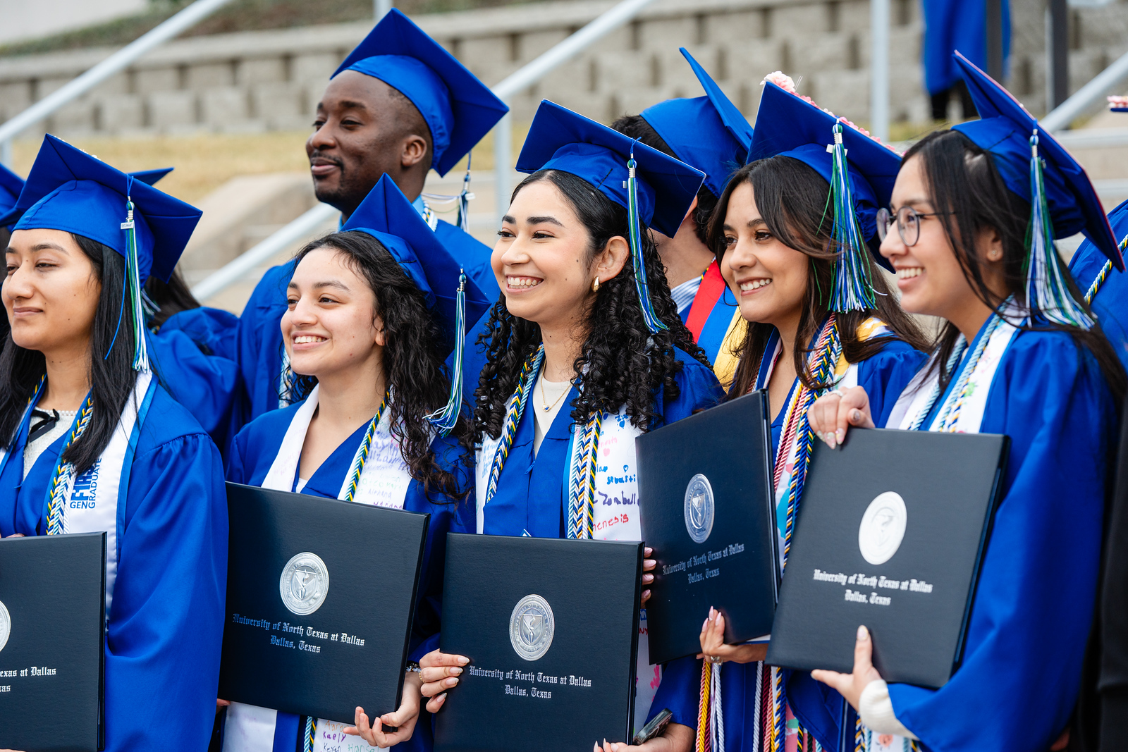 Photo of UNT Dallas graduates holding their diplomas and celebrate following the Fall 2025 Commencement Ceremony