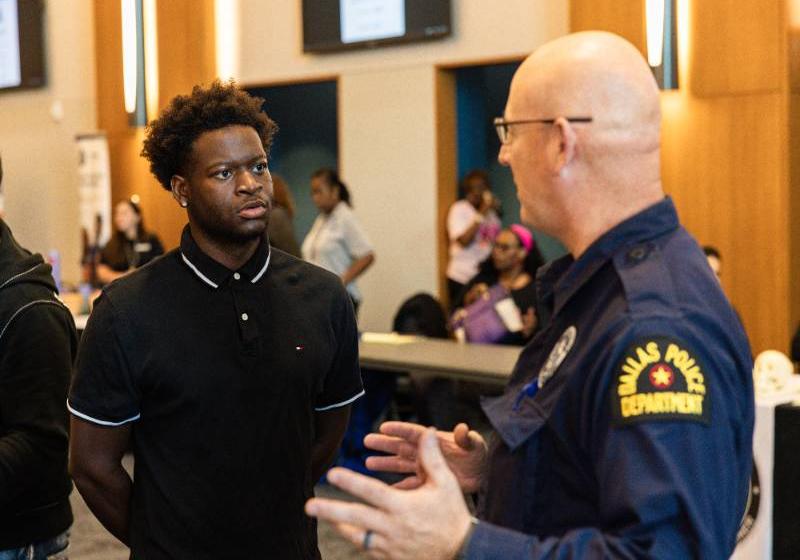 Photo of a UNT Dallas student talking with a Dallas police officer during a UNT Dallas Criminal Justice and Public Safety Expo.