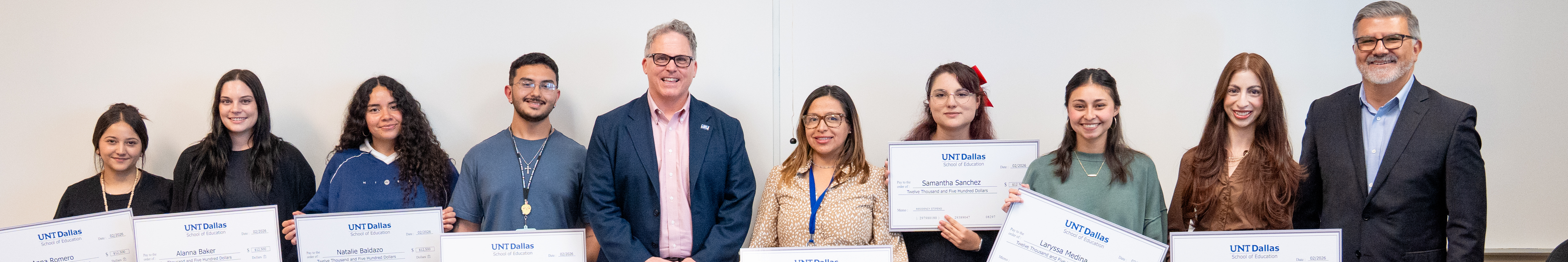 Banner photo of UNT Dallas President Warren von Eschenbach standing in the middle of a lineup consisting of Teacher Residency Program student celebration. Top horizontal cropped banner photo of UNT Dallas President Warren von Eschenbach standing in the middle of a lineup consisting of Teacher Residency Program students celebration.
