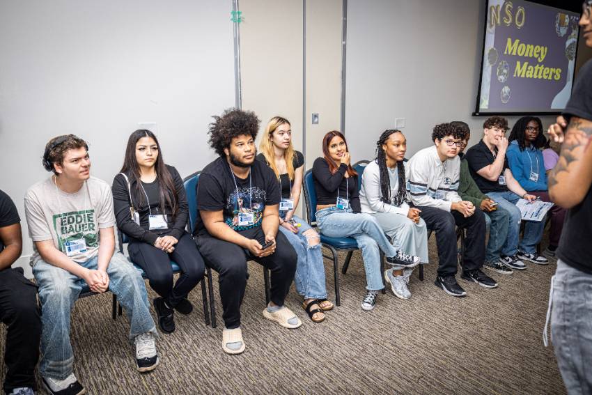 Photo of a row of seated new UNT Dallas students listen to an NSO Session about spending and saving money