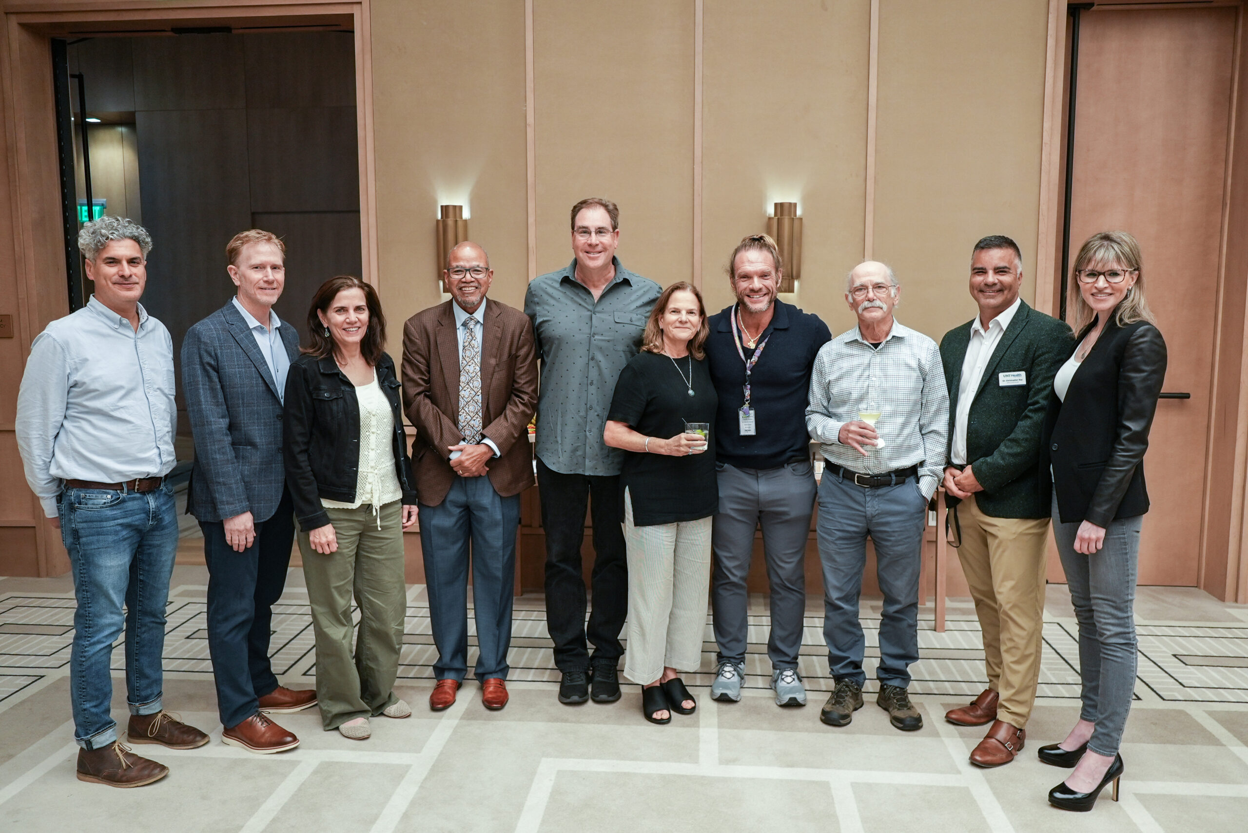 Uncropped: Smiling and posing for a photo are a group of nine people standing together from the UNT Health's Health and Aging Brain Study – Health Disparities event (fourth from left is UNT Health president, Dr. Calhoun).