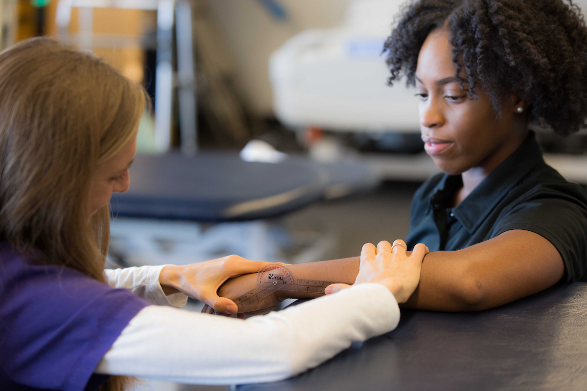 Photo of UNT Health's female physical therapy student is measuring the range of motion of a  patient's wrist
