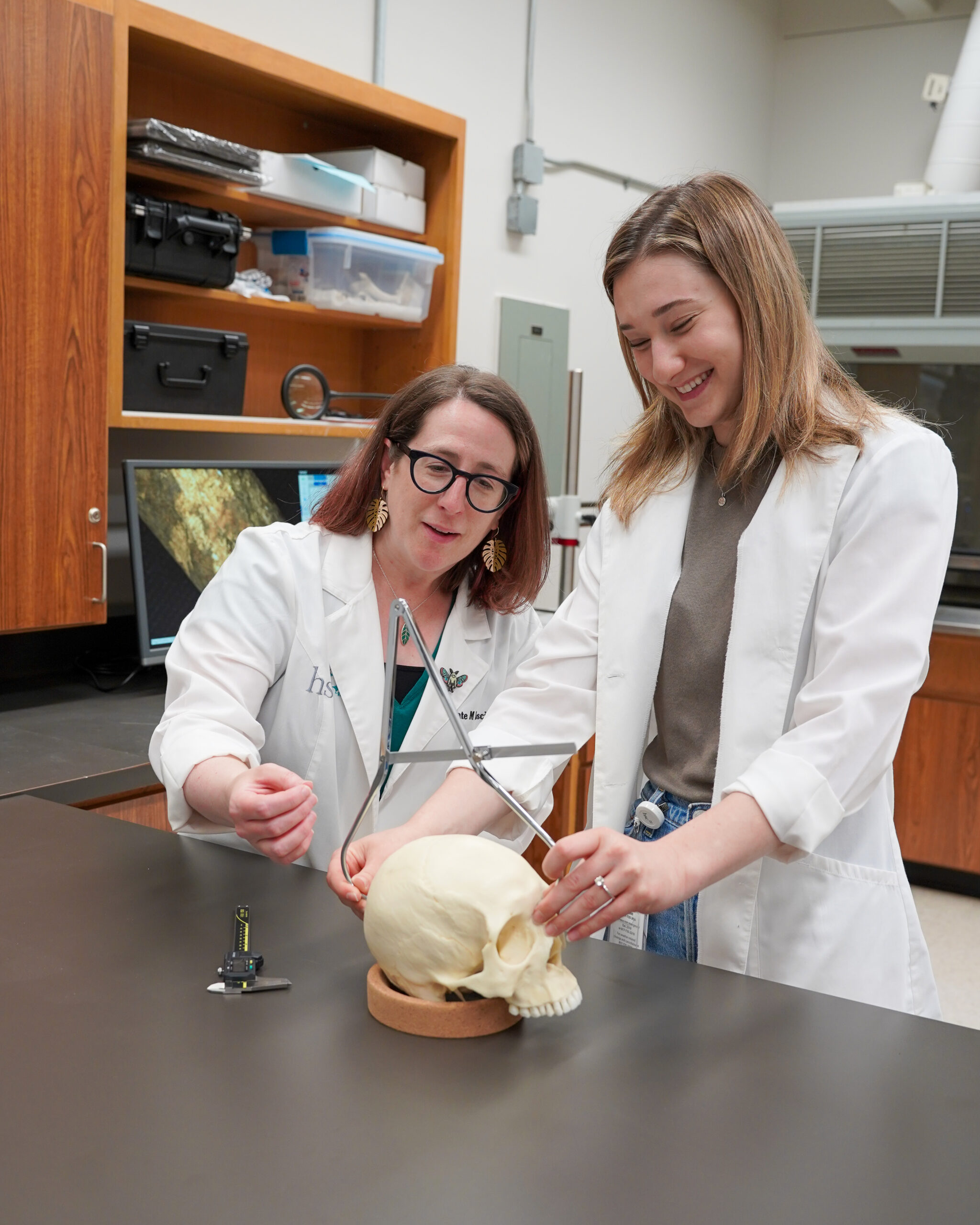 Photo of UNT Health's Dr. Kate Lesciotto in her lab with a student measuring a skull.