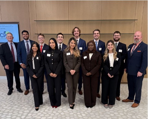 A different second team of 13 smiling UNT Health College of Public Health students and accompanying faculty, from the Master of Health Administration program. Photo showing a different second team of 13 smiling UNT Health College of Public Health students and accompanying faculty, from the Master of Health Administration program, each dressed in dark suit jacket and pants posing for their photograph. The back row consists of 8 men. The front row shows 5 woman.