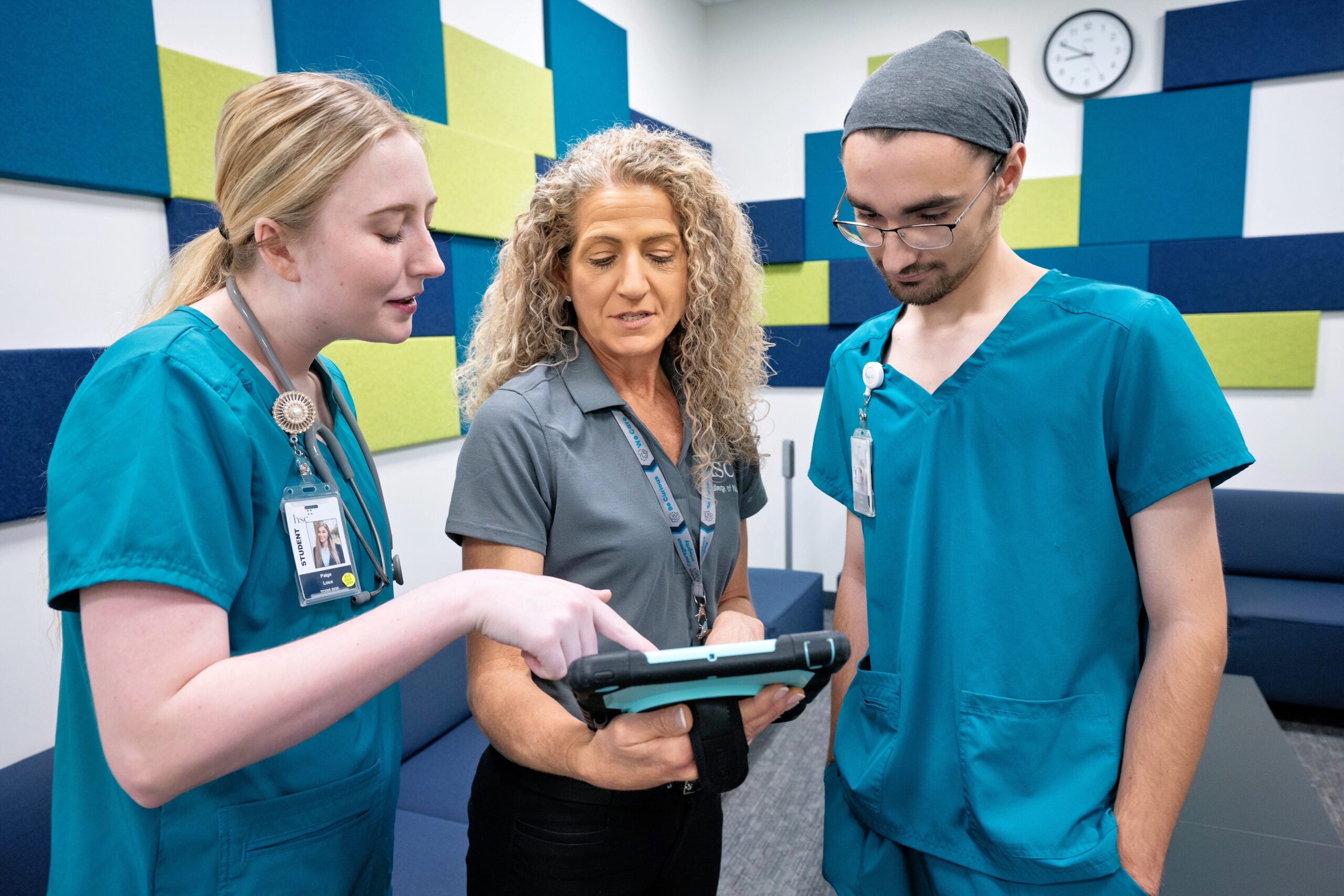 Photo of a nursing instructor reviews information on a tablet with two nursing students in a classroom at UNT Health Fort Worth's College of Nursing.