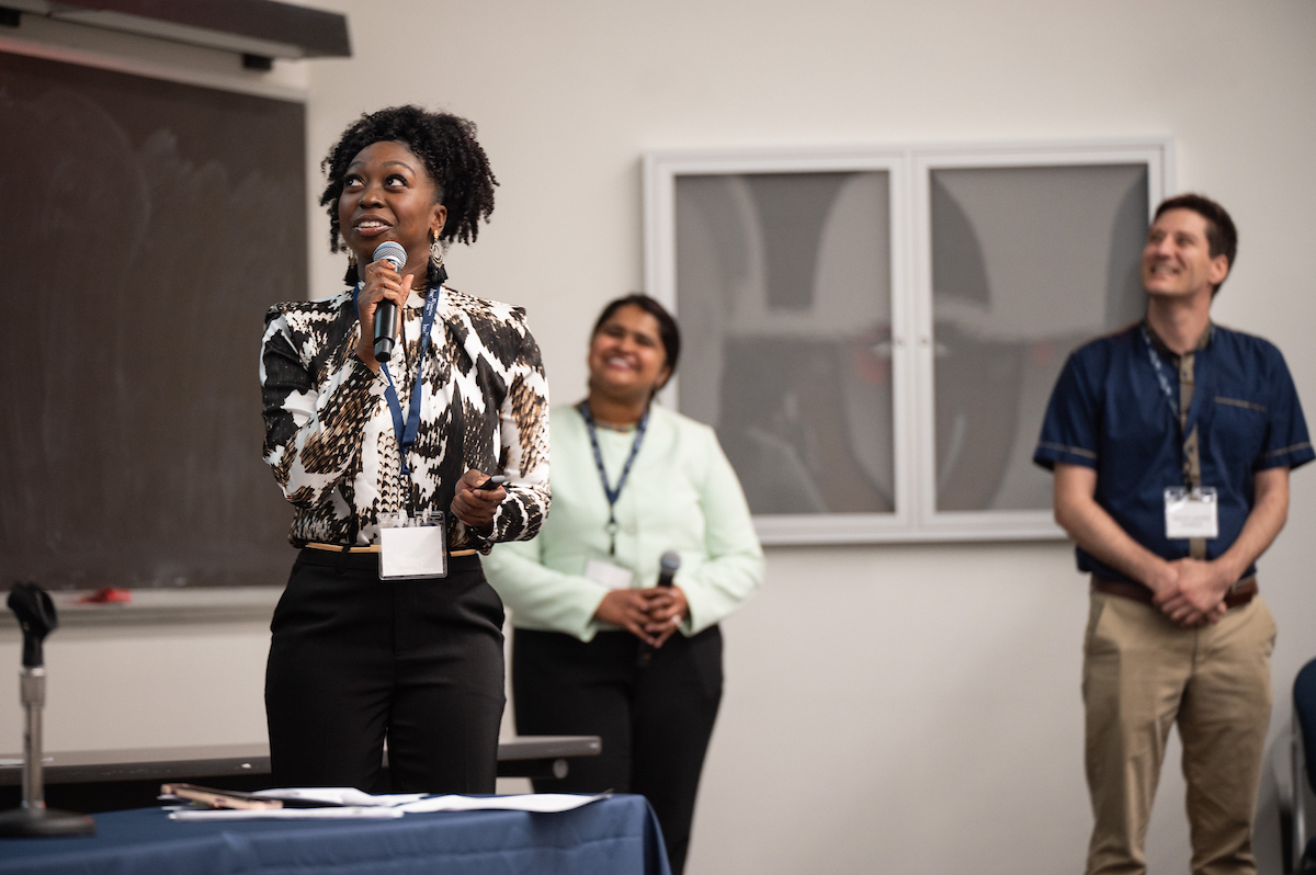 A photo of last year's UNT Health's 2025 patient safety conference where healthcare professional spoke at a patient safety conference with colleagues standing in the background.