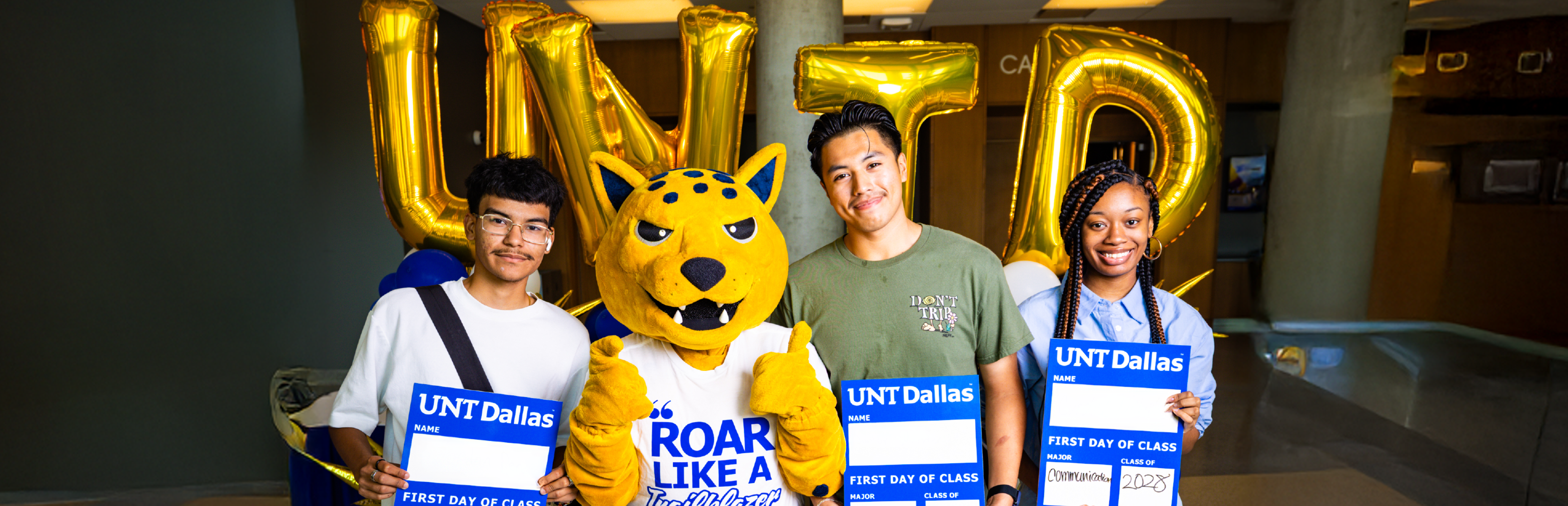 Photo showing 3 new UNT Dallas students on their first day of school posing with the jaguar mascot