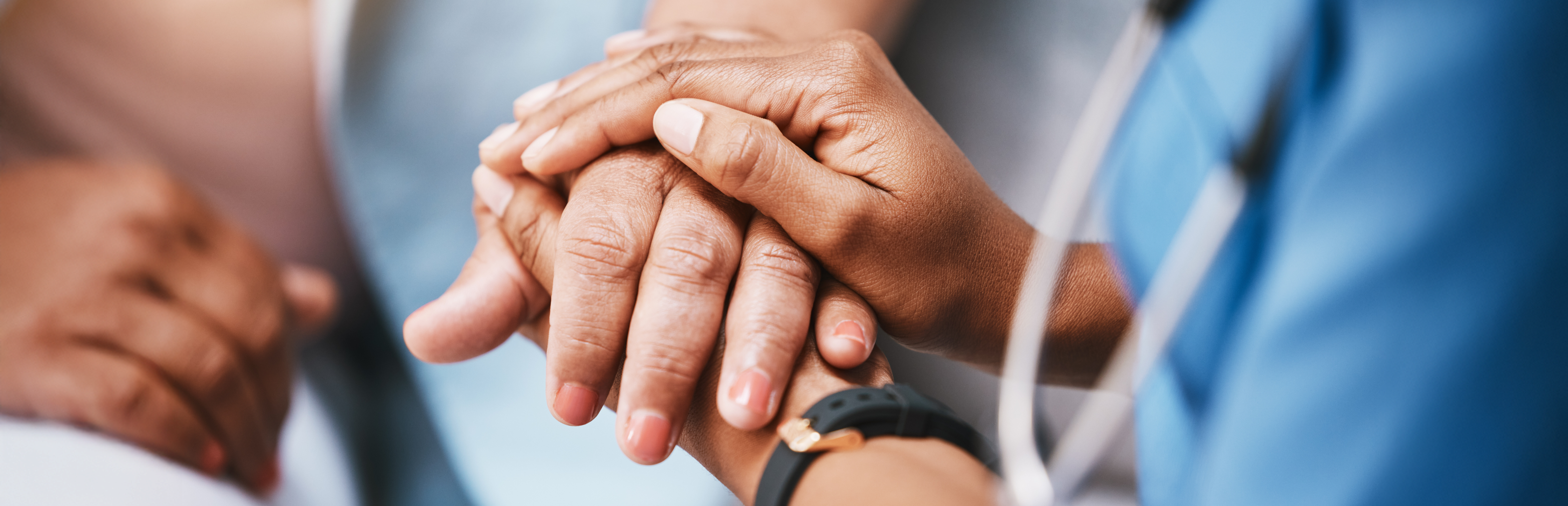 A UNT Health Texas Center for Patient Safety nurse gently holding a patient’s hands in a supportive gesture.