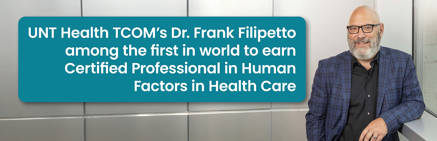 A promotional photo banner featuring Dr. Frank Filipetto, a smiling bald man with a gray beard wearing glasses and a navy plaid blazer, posed against a modern silver-paneled wall. A teal text box on the left reads: UNT Health TCOM's Dr. Frank Filipetto among the first in world to earn Certified Professional in Human Factors in Health Care.